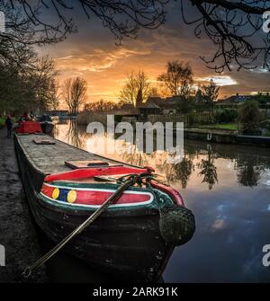 Ein altes schmales Jahrmarktboot, das in der Abenddämmerung entlang des Trent- und Mersey-Kanals, Cheshire, Großbritannien, gefestigt wurde. Stockfoto