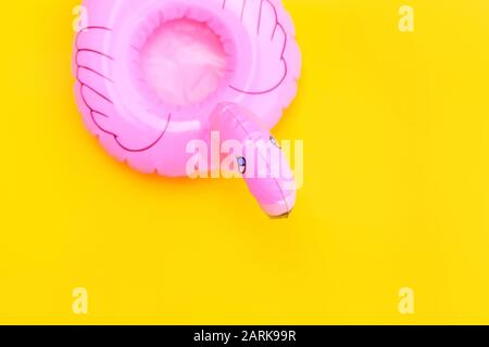 Strandzusammensetzung im Sommer. Einfach minimales Design mit pinkfarbenem, aufblasbarem Flamingo, der auf gelbem Hintergrund isoliert ist. Pool Float Party, modisches Promi-Modekonzept. Platz für Kopien in flacher Lage in der Draufsicht Stockfoto