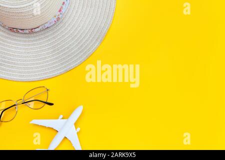 Strandzusammensetzung im Sommer. Minimale einfache flache Lage mit planaren Sonnenbrillen und Hut isoliert auf gelbem Hintergrund. Urlaub Reise Abenteuer Konzept. Kopierbereich in der Draufsicht Stockfoto