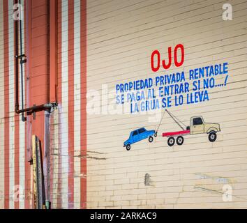 Die spanische Sprache, die auf die alte Mauer aus Backstein mit kindlicher Zeichnung und Warnung zum Parken auf Privatgrundstück oder Auto eingekesselt ist, wird von Tow TR geschleppt Stockfoto