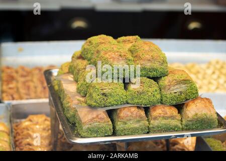 Sorten von Pistazienbaklava. Er wurde aus dem Fenster gezogen. Menschen, die im Hintergrund arbeiten. Nahaufnahme. Stockfoto