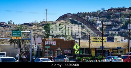 Blick auf die Innenstadt von Nogales, AZ, mit Vorhängen im Vordergrund und Grenzzaun auf einem Hügel mit Blick auf die Häuser auf der mexikanischen Seite von US-Mexikaner Stockfoto