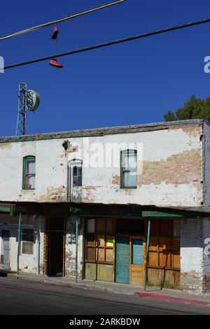 Rote Schuhe hängen aus dem Oberdraht in der Nähe eines trendigen, heruntergekommenen alten Gebäudes mit Schild für die Vermietung von Wohnungen, in der mexikanischen Grenzstadt Nogales, AZ, USA Stockfoto