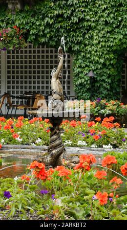 Eine aus Bronze gegossene Statue dient als Springbrunnen in einem Blumenteich im italienischen Garten in den Butchart Gardens. Stockfoto