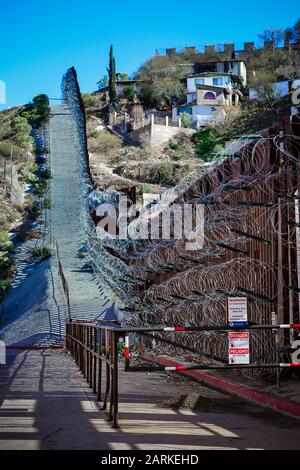 Blick auf den internationalen Metallgrenzzaun mit Stacheldraht nach dem Aufstieg zwischen Nogales, AZ, USA und Nogales, Sonora, MX, Stockfoto