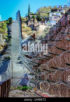 Blick auf den internationalen Metallgrenzzaun mit Stacheldraht nach dem Aufstieg zwischen Nogales, AZ, USA und Nogales, Sonora, MX, Stockfoto