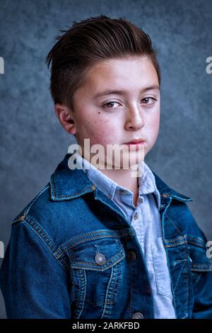 Gutaussehender asiatischer, asiatischer, junger, straffender Junge mit einem wütenden Stirnrunzeln, der eine blaue jeans-jacke mit gefetteten Haaren trägt Stockfoto