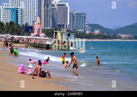 An einem heißen, sonnigen Tag genießen die Menschen die Promenade und den Strand am Badeort Nha Trang in Vietnam, Südostasien, Indochina, Asien. Was den Kahn im Hintergrund betrifft: Im Dezember 2019 driftete ein Fährkahn mit der Nummer KH-98668-TS und wurde in den Strand von Nha Trang gespült und steckt noch am Sand östlich der Tran Phu Street, Nha Trang, am 29. Januar 2020 fest. Stockfoto