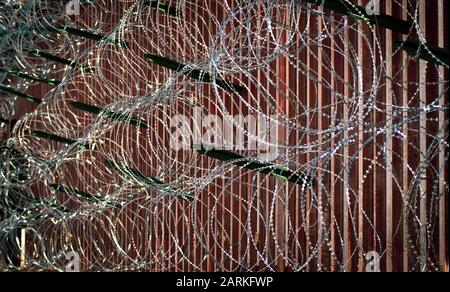 Nahaufnahme des internationalen Grenzzauns aus Metall in den USA/Mexiko mit Rasierdraht in Nogales, AZ, USA Stockfoto