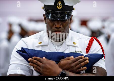 190906-N-PL946-1213 GROSSE SEEN, Illinois (Sept. 6, 2019) Chief Fire Controlman (Aegis) Daniel Rainmaker, ein Kommandeur der Rekrutierung, hält die amerikanische Flagge vor einer Flaggenpräsentationsfeier in Erinnerung an den 11. September während einer Abschlussfeier im Recruit Training Command (RTC). RTC präsentierte die Flagge Kenneth Corrigan, einem Veteranen der Marine und Ersthelfer bei den Anschlägen vom 11. September auf das World Trade Center. Mehr als 35.000 Rekruten trainieren jährlich im einzigen Bootcamp der Marine. (USA Navy-Foto von Mass Communication Specialist 1st Class Spencer Fling) Stockfoto