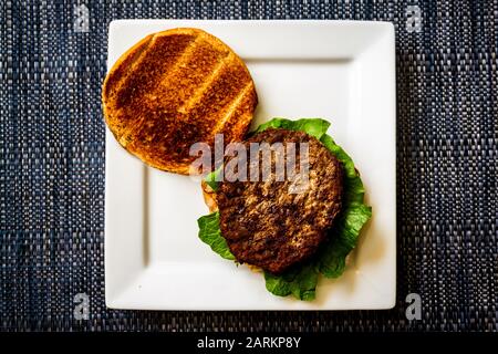 Ein schlichter hamberger auf einem weißen Teller Stockfoto
