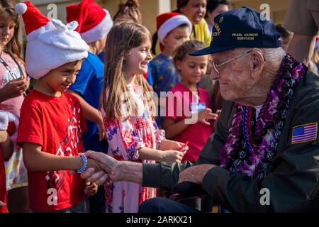 Donald Long, pensionierter Radiomoderator der US Navy, schüttelt einen Studenten mit der Hand der Mokapu Elementary School während seines Besuchs auf der Marine Corps Base Hawaii (MCBH), 5. Dezember 2019. Die Best Defence Foundation brachte 6 Perlhafen- und Marinefliegerstationen Kaneohe Bay Survivors aus dem zweiten Weltkrieg für das 78. Gedenken an Pearl Harbor und die Naval Air Station Kaneohe Bay, die heute MCBH ist, nach Hawaii zurück. Die zurückkehrenden Helden waren Jack Holder (97) US NAVY - Naval Air Station, Kaneohe Bay; Tom Foreman (98) US Navy - USS Cushing; Ira Schab (99) US Navy - USS Dobbin; Stuart Hedley (98) US Navy - USS West Virginia; Donald Long (98) Stockfoto