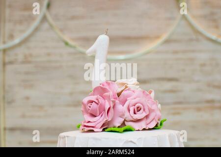 Oberteil mit luxuriösem Kuchen mit Rosen und einer einjährigen weißen Kerze auf hellem Holzhintergrund. Celebration Concept. Stockfoto