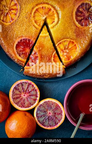 Hausgemachter, auf dem Kopf geblackener Orangenkuchen mit blutrorangenem Sirup auf Schiefergrund Stockfoto