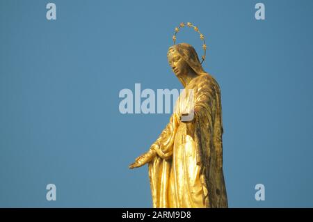 Nahaufnahme der goldenen Madonnina-Statue (Madonna - Immacolata) gegen den blauen Himmel am Hafen von Luino in der Lombardei, Italien Stockfoto