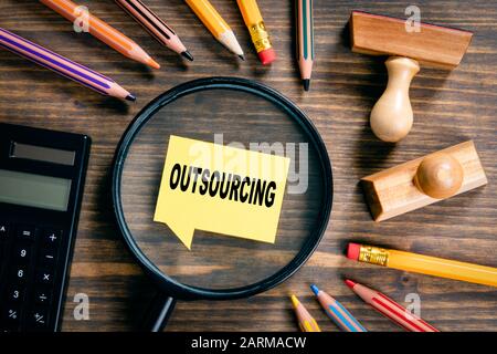 Outsourcing. Konzept für Service, Sicherheit, Steuern, Berichte und Empfehlungen. Lupe auf Holztisch Stockfoto