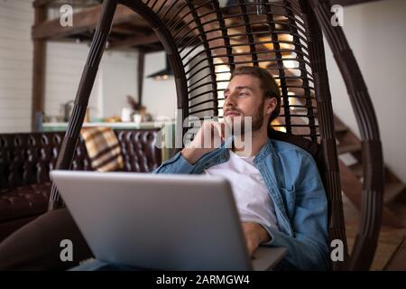 Nachdenklicher Mann, der in dem ungewöhnlichen Sessel arbeitet Stockfoto