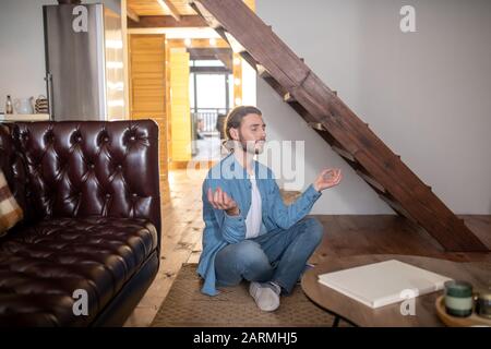 Entspannter junger Mann, der in seinem Apartment meditiert Stockfoto