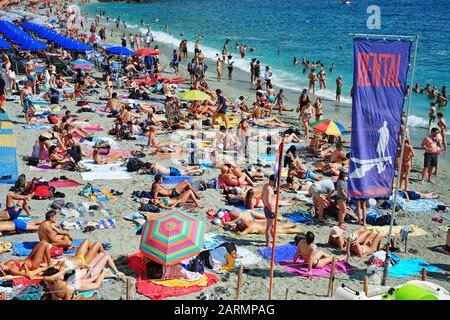 Am öffentlichen Strand von Monterosso werden an einem heißen Sommertag in der Cinque Terre, der italienischen Riviera, die sonnenliebenden Feriengäste in der Umgebung mit Farbe verwöhnt Stockfoto