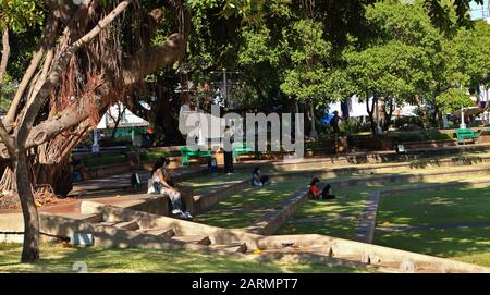 Bangkok, Thailand-28. Januar 2020: Gruppe von Menschen, die im Schatten des Baumes im öffentlichen Park von Santi Chai Prakan in der Nähe des Chao Phraya Flusses sitzen und sich entspannen Stockfoto