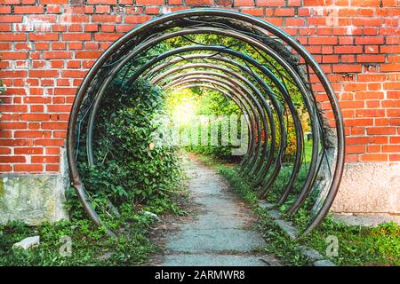 Abstraktes symbolisches Portal oder Durchgang in roter Ziegelwand aus kreisförmigen Metallstäben Stockfoto