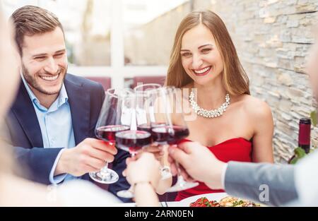 Leute, die auf dem Tisch des Restaurants sitzen und mit Rotwein toben Stockfoto