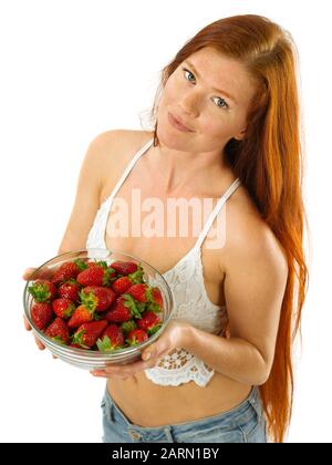 Foto von eine wunderschöne junge Frau mit langen roten Haaren Holding eine Schüssel Erdbeeren auf weißem Hintergrund. Stockfoto