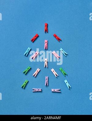 Bunte Wäscheklappen in Form von weihnachtsbaum auf blauem Hintergrund mit Kopierraum. Draufsicht. Stockfoto