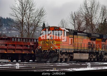 Eine schwarze, gelbe und orangefarbene BNSF-Lok, die im Leerlauf auf den Gleisen in der Stadt Troy, Montana, fuhr. Burlington Northern and Santa Fe Railway wurde in gebildet Stockfoto