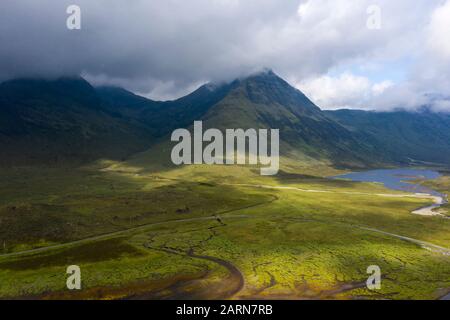 Luftaufnahme auf einem Meeresgrund auf der Insel Skye bei Ebbe. Der hohe Berg mit dramatischen Wolken gibt dem Bild eine spannende Tiefe Stockfoto