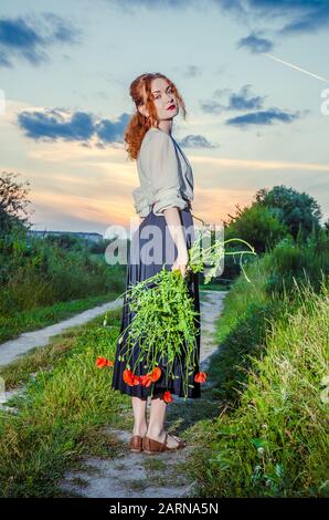 Schöne braungebrannte Mädchen in weißen besticktes Kleid Holding in den Händen Blumenstrauß der ährchen. Glücklich lächelnde Frau Spaß haben, Wandern auf dem Feld. Konzept Stockfoto