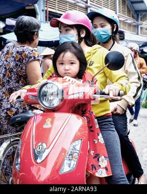 Motorräder sind in Vietnam allgegenwärtig. Diese junge Familie auf einem Roller befindet sich mitten in Sa Dez Fahrt durch den Straßenmarkt. Stockfoto