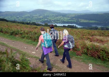 Drei Frauen, Die Auf einer Strecke auf Barton Spazieren, Fielen über den Ullswater Lake zum Wainwright 'Arthurs Pike' im Lake District National Park, Cumbria. Stockfoto