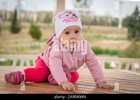 Porträt eines niedlichen kleinen Mädchens, das an einem übergiebelten Tag auf einem Holztisch in einem Sommerhaus sitzt Stockfoto