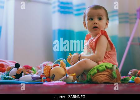 Ein niedliches kleines Mädchen, das mit Spielzeug auf dem Boden in ihrem Zimmer zu Hause spielt. Stockfoto