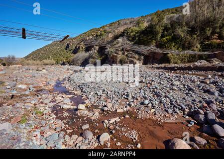 Wacklige Holzbrücke über den Fluss Ourika hoch oben im Atlas-Gebirge in Marokko Stockfoto