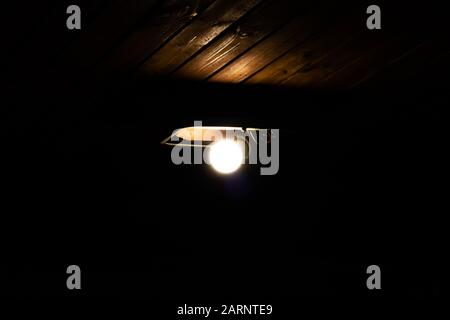 Alte Lampe an einer Holzdecke im Dunkeln Stockfoto