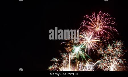 Mehrere weiße Starburst-Feuerwerke mit roten, grünen und goldenen Höhepunkten, die am vierten Juli in Minnesota gegen einen schwarzen Himmel fotografiert wurden Stockfoto