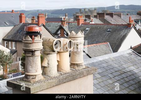 Kamintöpfe und Dächer in einer typischen walisischen Stadt in Großbritannien. Mit kunstvollen viktorianischen Cowls. Conwy, Wales Stockfoto