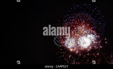Große rote, weiße, blaue und goldene Feuerwerke, die am vierten Juli in Minnesota gegen einen schwarzen Himmel fotografiert wurden Stockfoto