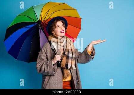 Foto der hübschen Reisendame mit farbenfrohem Sonnenschirm Walk Street Scheckarm, wenn Regen aufgehört hat modische Freizeit lang grau Mantel Pullover Hosen Hut Plaid Stockfoto