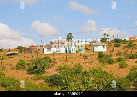 Wohnhäuser im Dorf an der Straße zwischen St. Lucia und Imfolozi-Hluhluwe National Park, KwaZulu Natal, Südafrika. Stockfoto