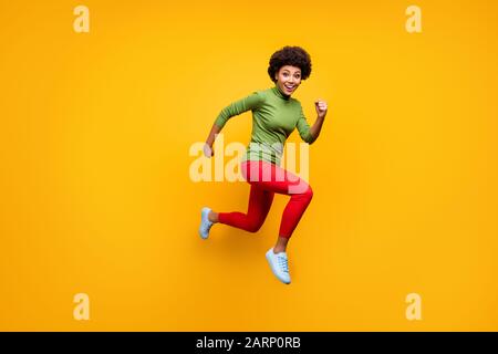 Durchgehende Körpergröße gedrehtes Foto von fröhlicher süßer Freundin dringend für vergünstigte Käufe in roter Hose weißer Fuß tragen springenden Lauf Stockfoto