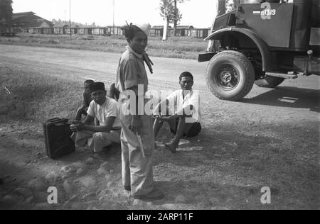 Reinigungsaktionen Pekalongan W-Brigade Zwei indonesische Männer und zwei Jungen sitzen auf dem Boden entlang der Seite der Straße. Ein Behälter für sie. Im Erdgeschoss ein indonesischer Mann in Uniform, der eine Art kris oder Messer hält. Ein Armee-Lastwagen auf der rechten Seite. In der Ferne ein Bahnhof mit Eisenbahnwaggons Datum: 16. August 1948 Standort: Indonesien, Niederländisch-Ostindien Stockfoto