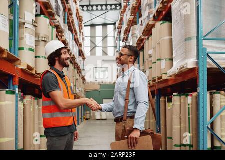 Banker und Unternehmer schütteln in einer modernen Fabrik die Hände - zwei Männer machen einen Deal Stockfoto