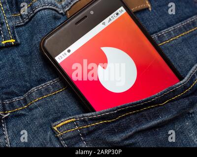 In dieser Abbildung wird das Tinder Social Network-Logo auf einem Smartphone in Jeansschümpel dargestellt Stockfoto