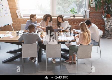 Freundliches Business Team, das am Tisch sitzt und ein Meeting hat Stockfoto