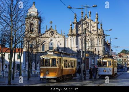 Traditionelle Straßenbahnen in der Pfarrei Vitoria in Porto, Portugal. Karmelitenkirche (Igreja dos Carmelitas Descalcos), Carmo-Kirche (Igreja do Carmo) im Hintergrund Stockfoto