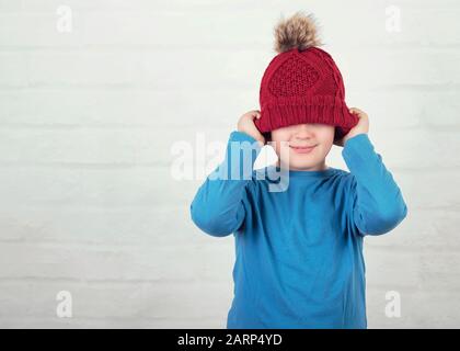 Lustig Kind mit Winter Hut auf backstein Hintergrund Stockfoto