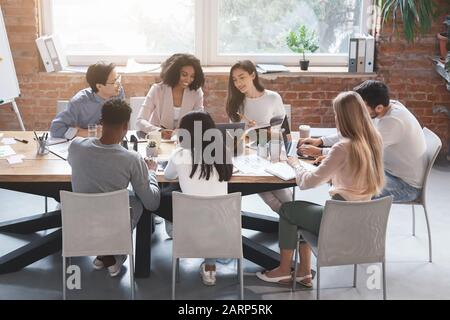 Kreative internationale Mitarbeiter diskutieren über neues Projektbüro Stockfoto